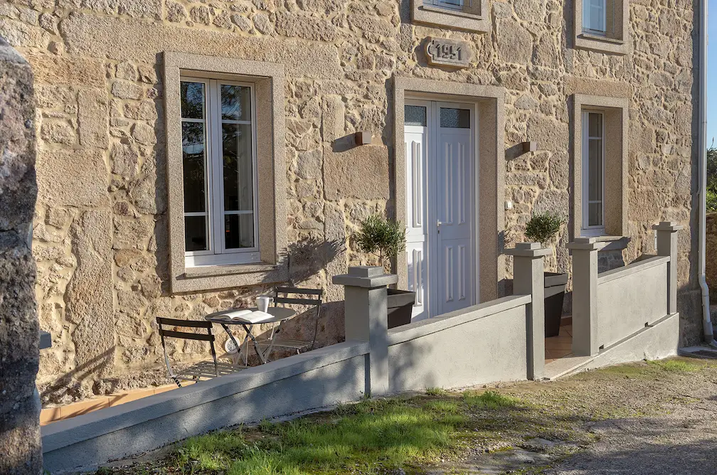 Fachada de una casa de piedra con puerta blanca, reflejando el estilo arquitectónico tradicional y rustico